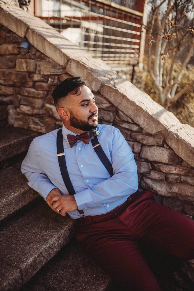 Groom in blue button up shirt and maroon bowtie with suspenders in northwest arkansas