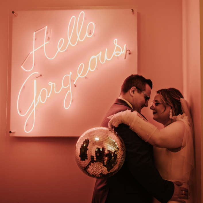 bride and groom in front of neon sign with disco ball in Lubbock, TX